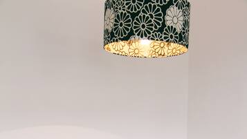 Une table à manger avec des chaises bleues, une plante en pot et une suspension aux motifs noir et blanc.