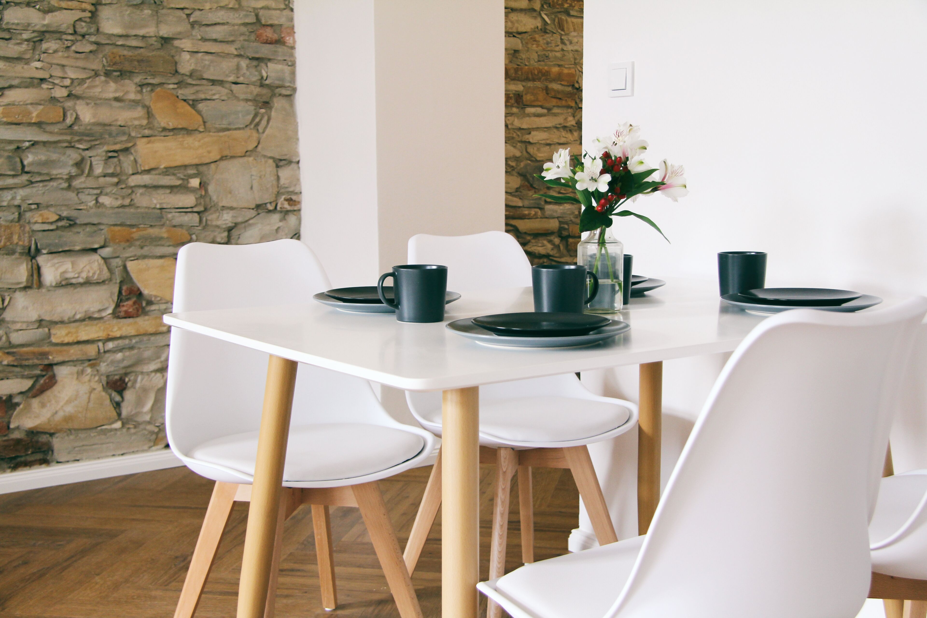 A dining area with a white table, black plates, and white chairs.