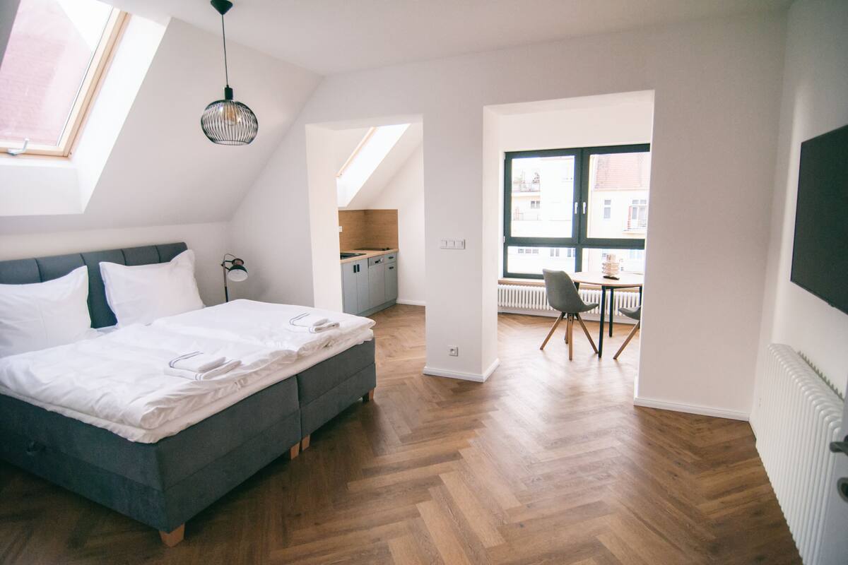 A bedroom with a bed, a desk, and a view of the city.