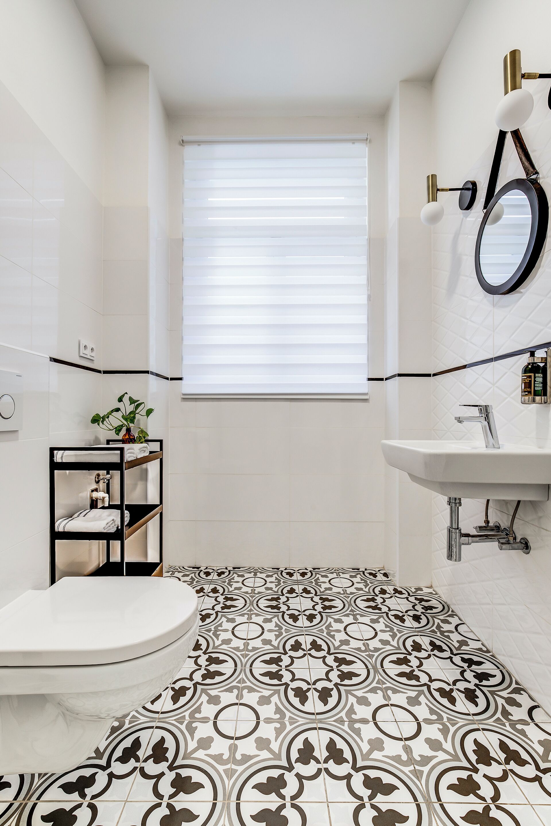 A bathroom with a toilet, sink, and a window with blinds.
