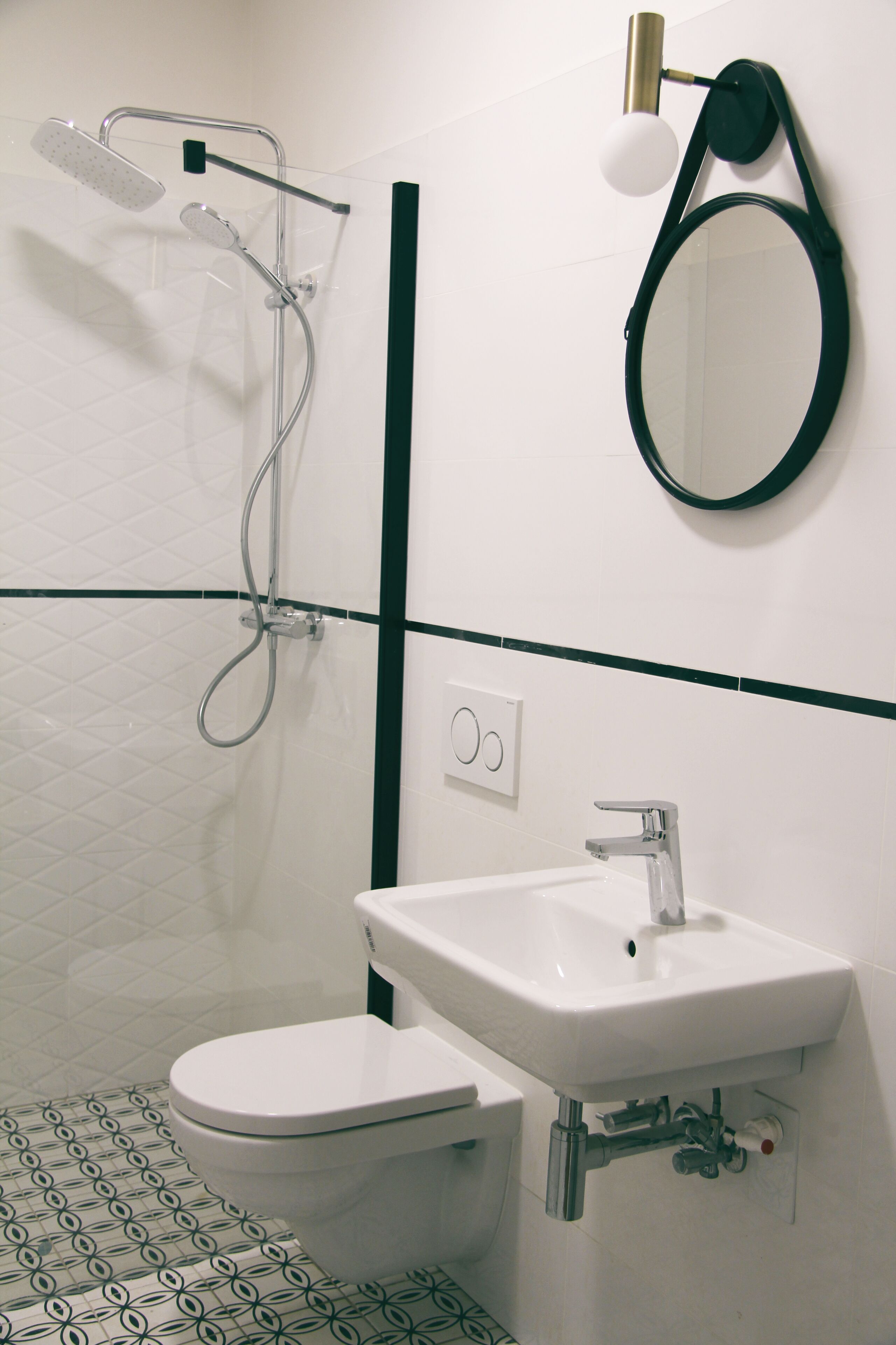 A bathroom with a white toilet, a sink, a mirror, and a shower.