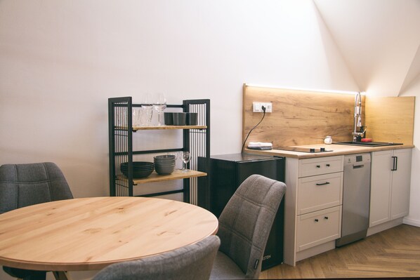 A modern kitchen with a wooden countertop, a built-in dishwasher, and a small shelf with kitchenware. - Design Pension Twenty (Podebrady)