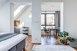 Quarto moderno com cama, escrivaninha e área de refeições.