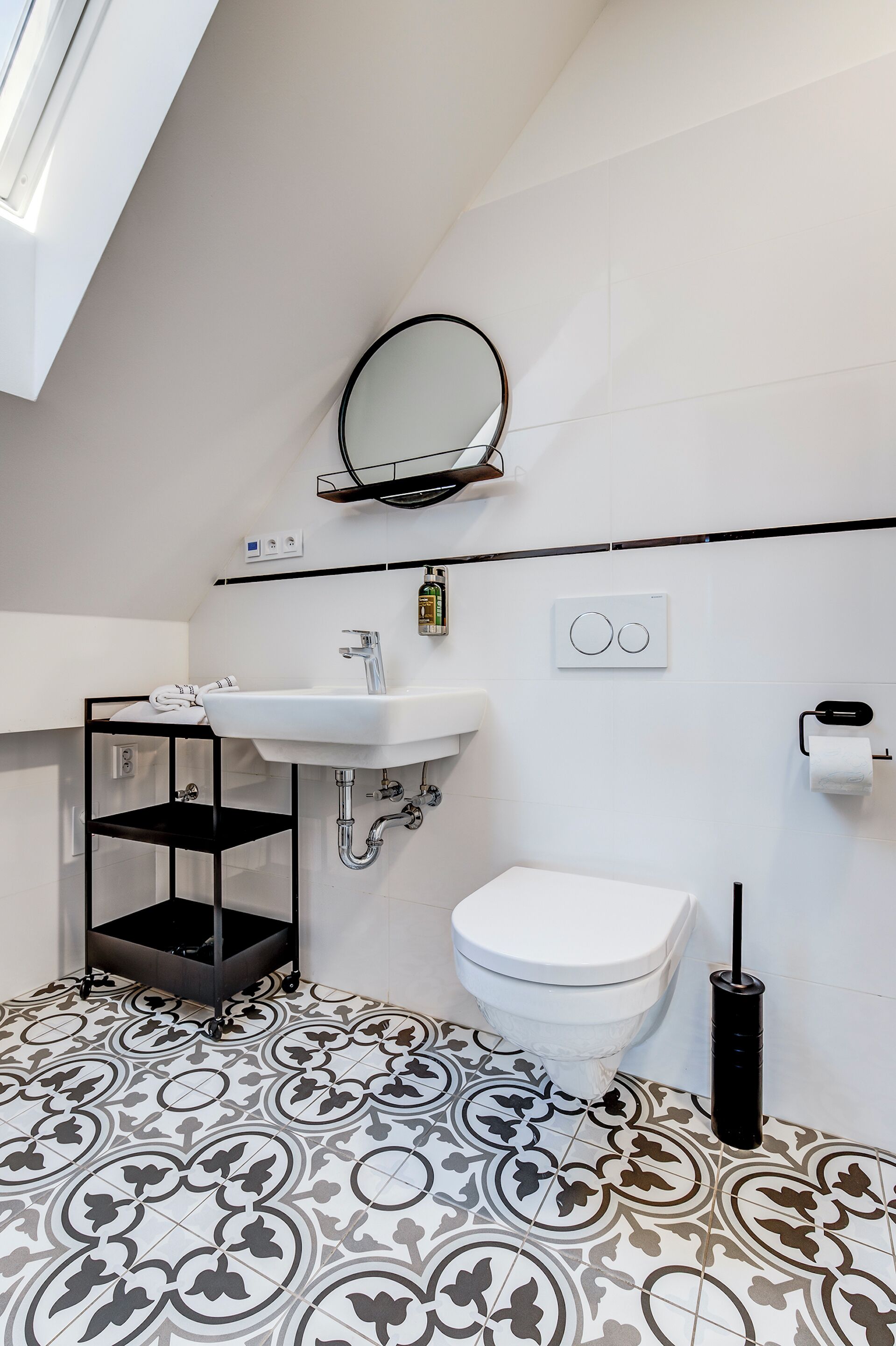 Un bagno moderno con lavandino bianco, water e piastrelle a pavimento decorate.