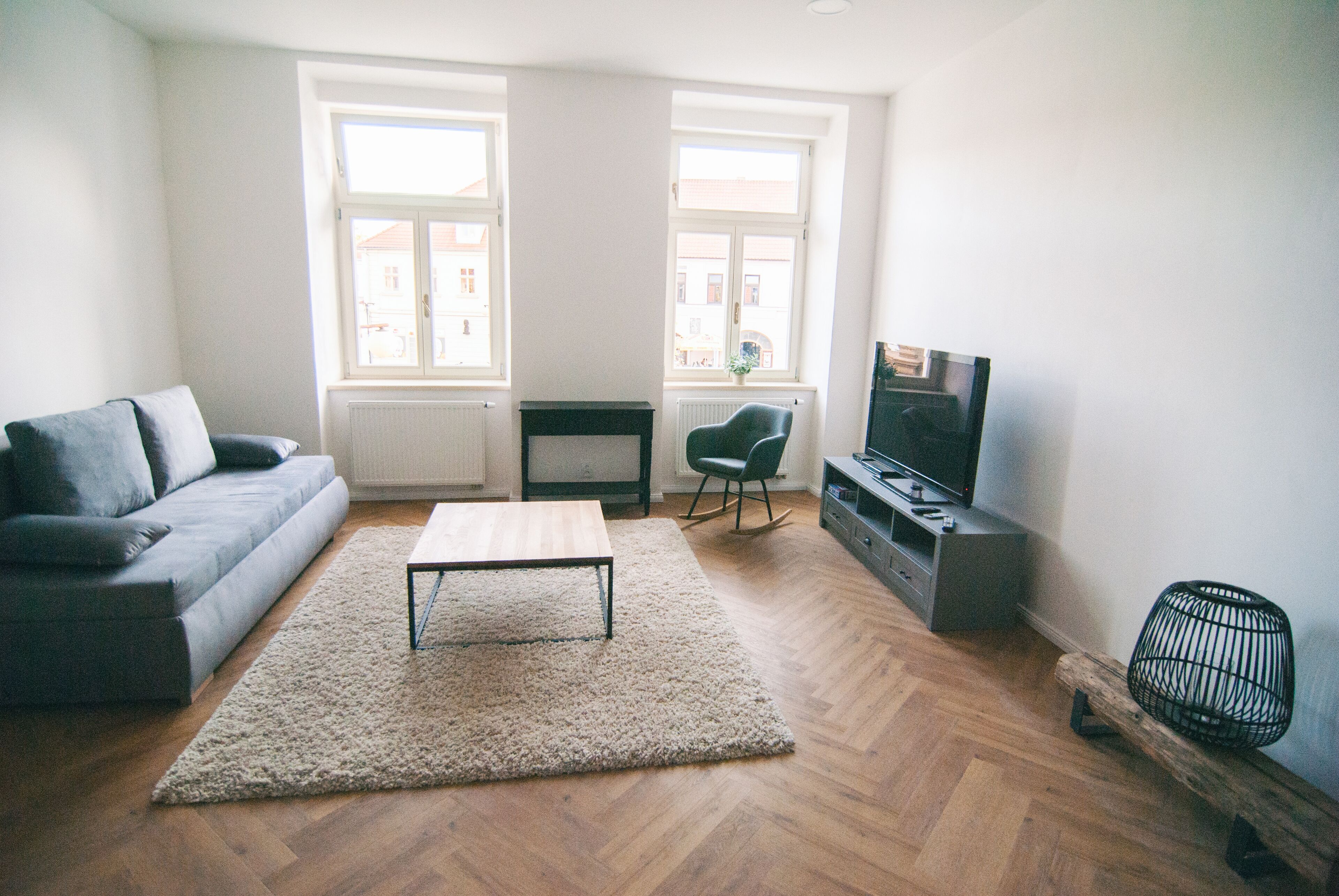 A living room with a sofa, a coffee table, a TV, and a radiator.