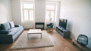 A living room with a sofa, a coffee table, a TV, and a radiator.