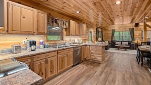 A wooden cabin interior with a kitchen, dining area, and living room. - Beside Still Water 1 - 2 Bedrooms, 2 Baths, Sleeps 6 Home by RedAwning (Cosby)