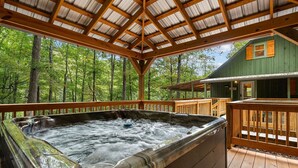 A hot tub area with a wooden deck and a view of a forested area. - Beside Still Water 1 - 2 Bedrooms, 2 Baths, Sleeps 6 Home by RedAwning (Cosby)