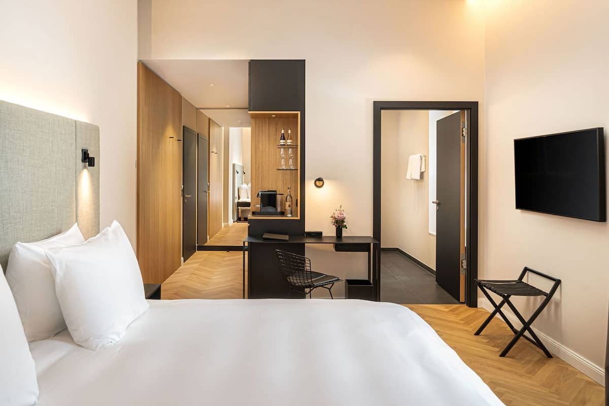 Ein Hotelzimmer mit einem großen Bett, einem Schreibtisch mit Stuhl, einem Fernseher und einem Spiegel.