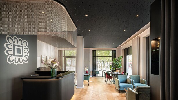 A modern hotel lobby with a reception desk, seating area, and large windows. - ESPLANADE Saarbrücken (Saarbrücken)