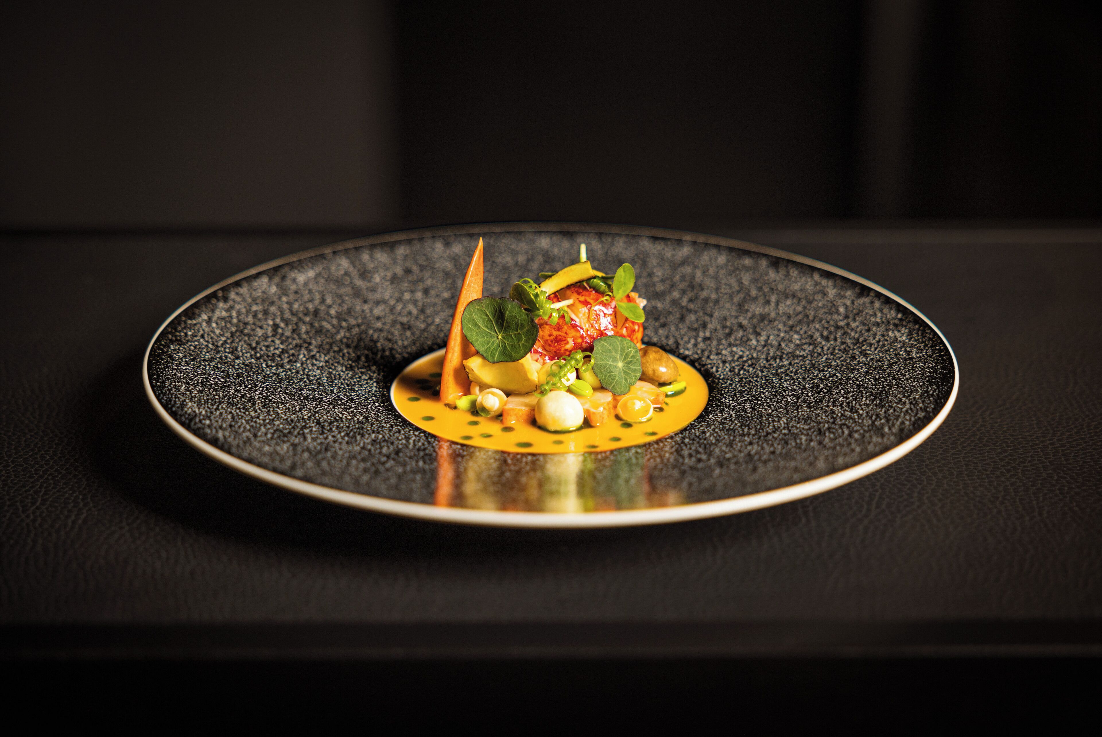 A dish on a black plate with a textured surface.