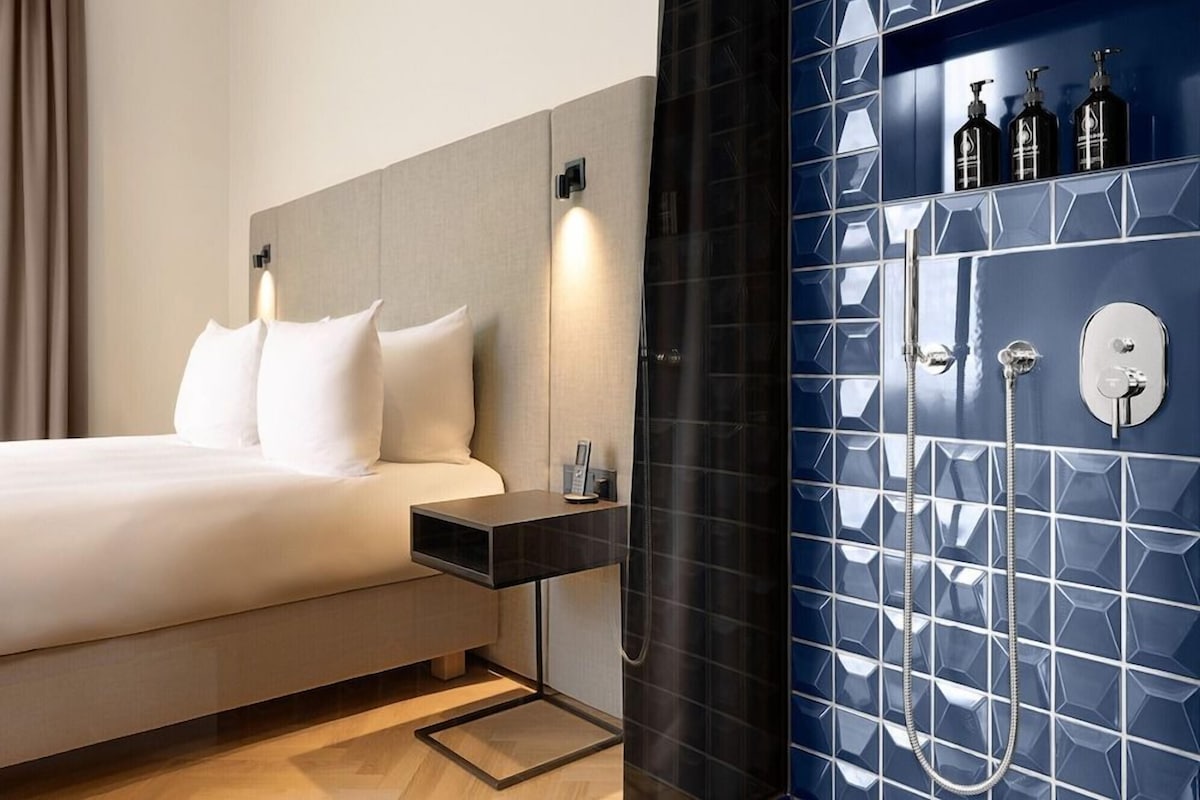 Ein Hotelzimmer mit Bett, Nachttisch und einem Badezimmer mit Dusche und Toilette.