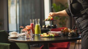 A table set for a meal with a cup, a vase with a flower, a green drink, and a tiered dessert stand. - ESPLANADE Saarbrücken (Saarbrücken)
