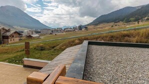 A mountainous landscape with buildings, a gravel area, and a wooden deck. - Apartment Amilu - beautiful 7/9 person ski-in, ski-out (Montgenèvre)