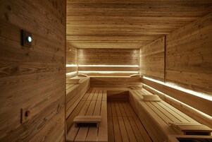 Una sauna con bancos de madera y paredes de madera, además de un banco en el centro.