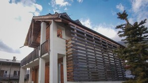 A modern building with a balcony, a wooden slatted wall, and a clear sky.