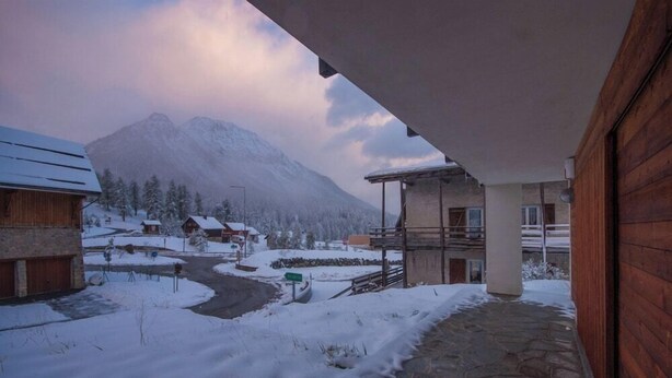 A snow-covered mountain landscape with a wooden building and a stone pathway.