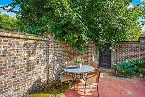 Enjoy a serene outdoor space with a brick wall, round table, and comfortable seating for four.