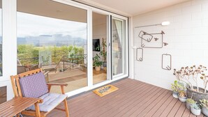 En balkon med træterrasse, stol og plantekasser.