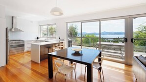 A modern kitchen with a large island, a dining area, and a view of a lake and mountains. - Churchill House Riverside Retreat near Long Beach (Sandy Bay)