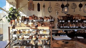 Une boulangerie où l’on peut admirer une variété de produits de boulangerie présentés sur des étagères et dans des plateaux.