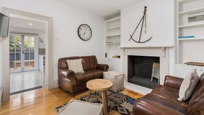 Un salon avec une cheminée, une horloge et une bibliothèque.