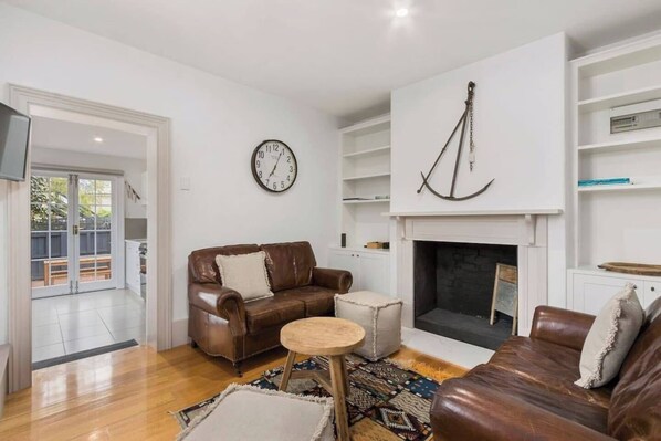A living room with a fireplace, a clock, and a bookshelf.