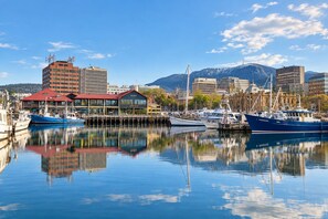A marina with boats docked, a building labeled 'MURES,' and mountains in the background. - Toris Cottage Stroll to Vibrant Salamanca (Battery Point)