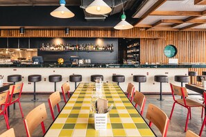 A restaurant with a long table, multiple bar stools, and a bar area with shelves of bottles. - Toris Cottage Stroll to Vibrant Salamanca (Battery Point)