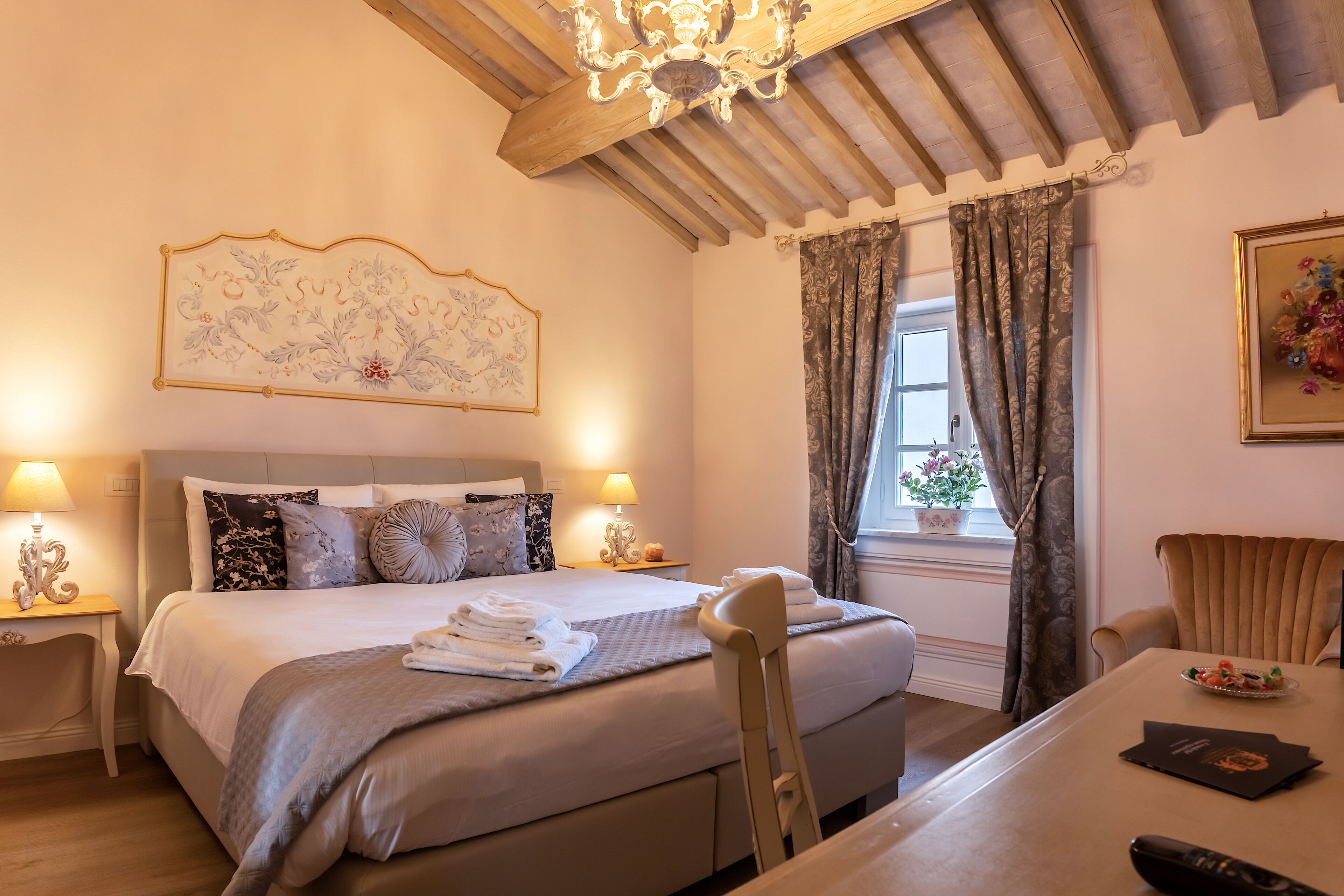 Un dormitorio elegante con una cama grande, lámparas de noche, una mesa de comedor y un candelabro.