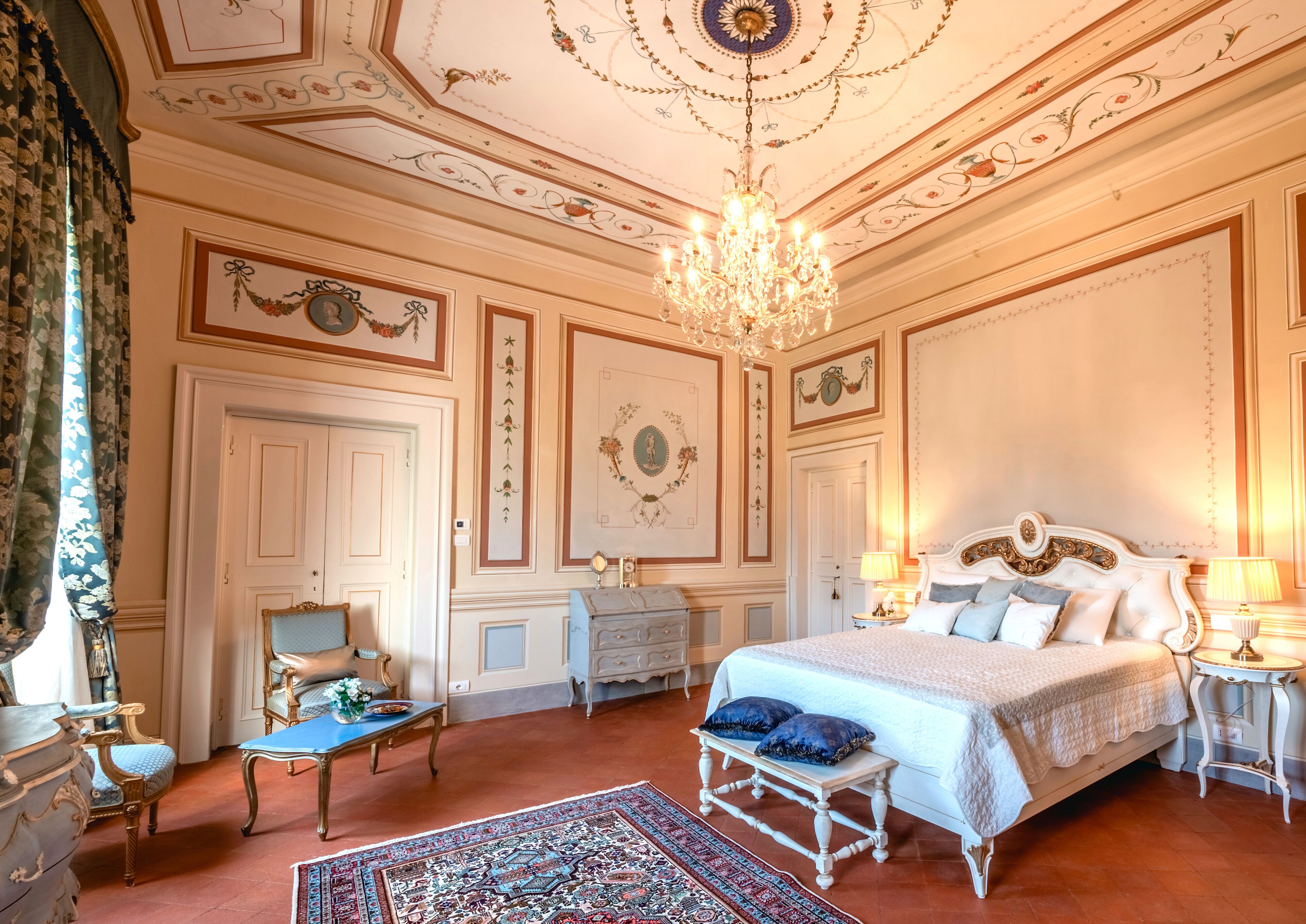 A luxurious bedroom with a large bed, ornate ceiling, and classic decor.