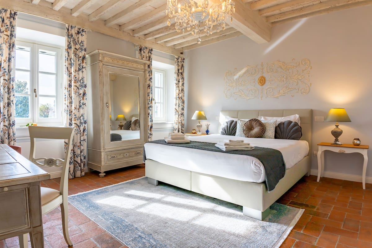 A bedroom with a large bed, a dresser, a chair, and a desk.