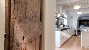A rustic wooden door leading into a modern kitchen with white cabinetry and pendant lighting.
