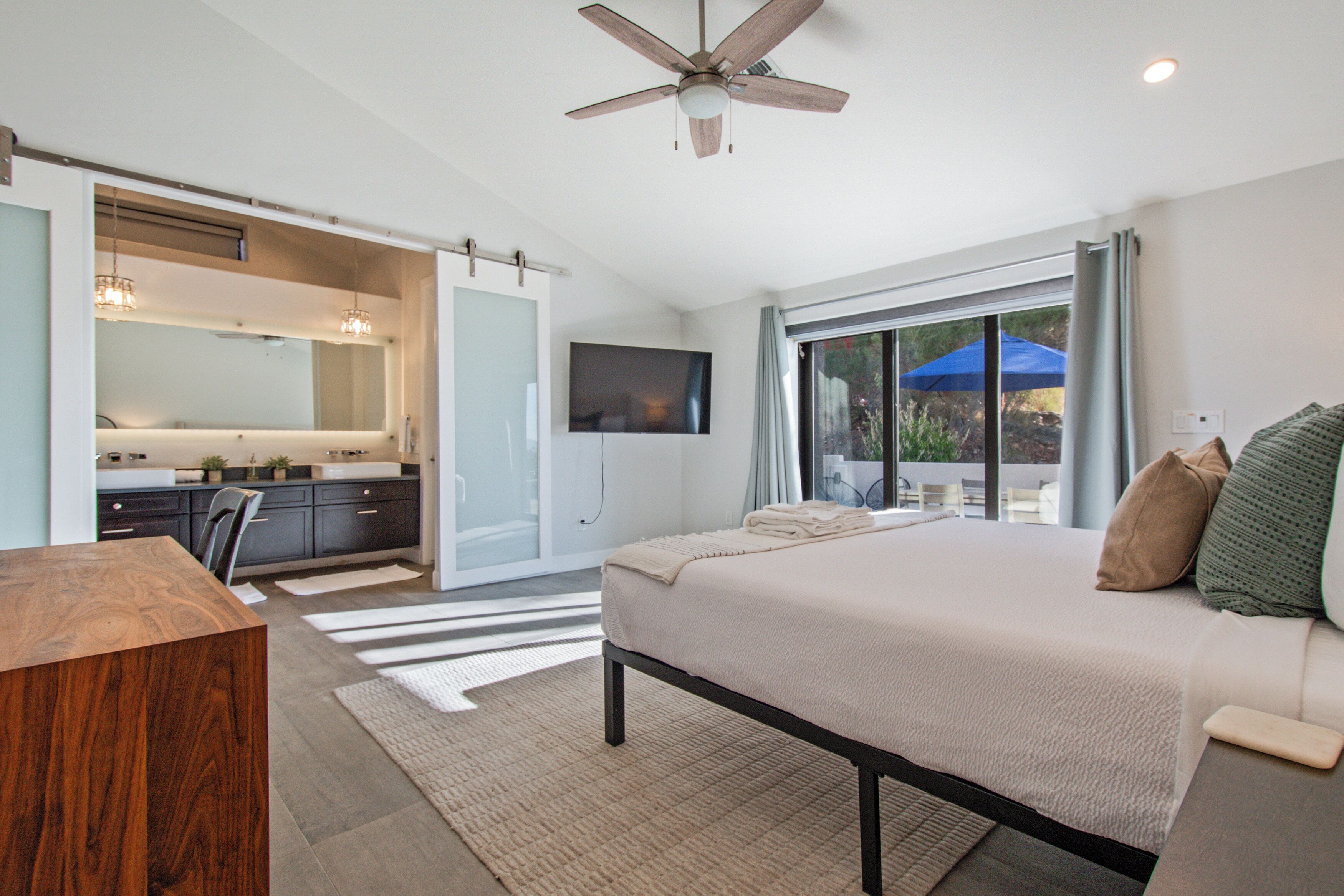 A bedroom with a bed, a desk, a chair, a TV, and a ceiling fan. - Skyline: 5 bed/6 bath, amazing views, tennis & basketball courts, pool, hot tub (Catalina Foothills)