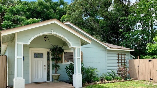 Een gelijkvloers huis met veranda, voordeur en een kleine tuin.