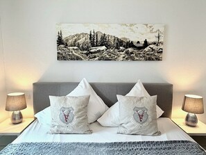 Ein Bett mit zwei Kissen, einem Wandbild und zwei Nachttischlampen.