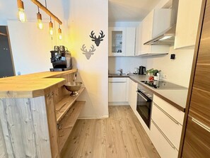 Une cuisine compacte dotée de plans de travail en bois, d  ’un four encastré et d’une machine à café.