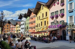 Eine Straße mit bunten Häusern, Außenplätzen und einer Uhr.