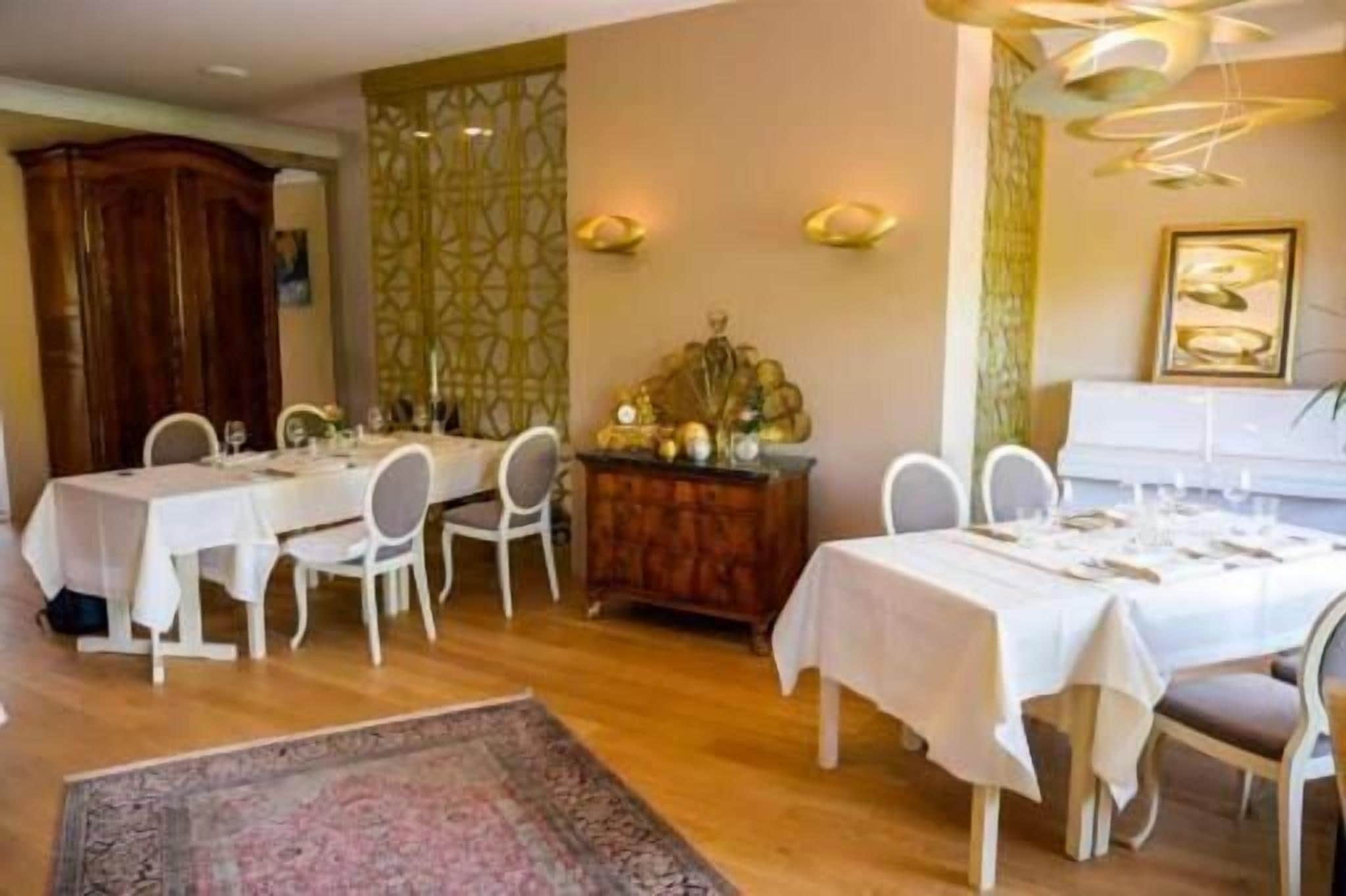 Un espace repas avec deux tables dressées pour le repas, chacune étant recouverte d’une nappe blanche et entourée de chaises.