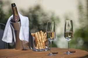 Dos copas de champán sobre una mesa de madera, con una botella de champán y un cuenco de galletas en el fondo.
