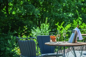 Una mesa al aire libre con sillas, una botella de champán y copas.