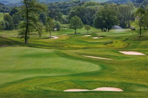Un campo de golf con bunkers de arena, árboles y un sistema de aspersión.
