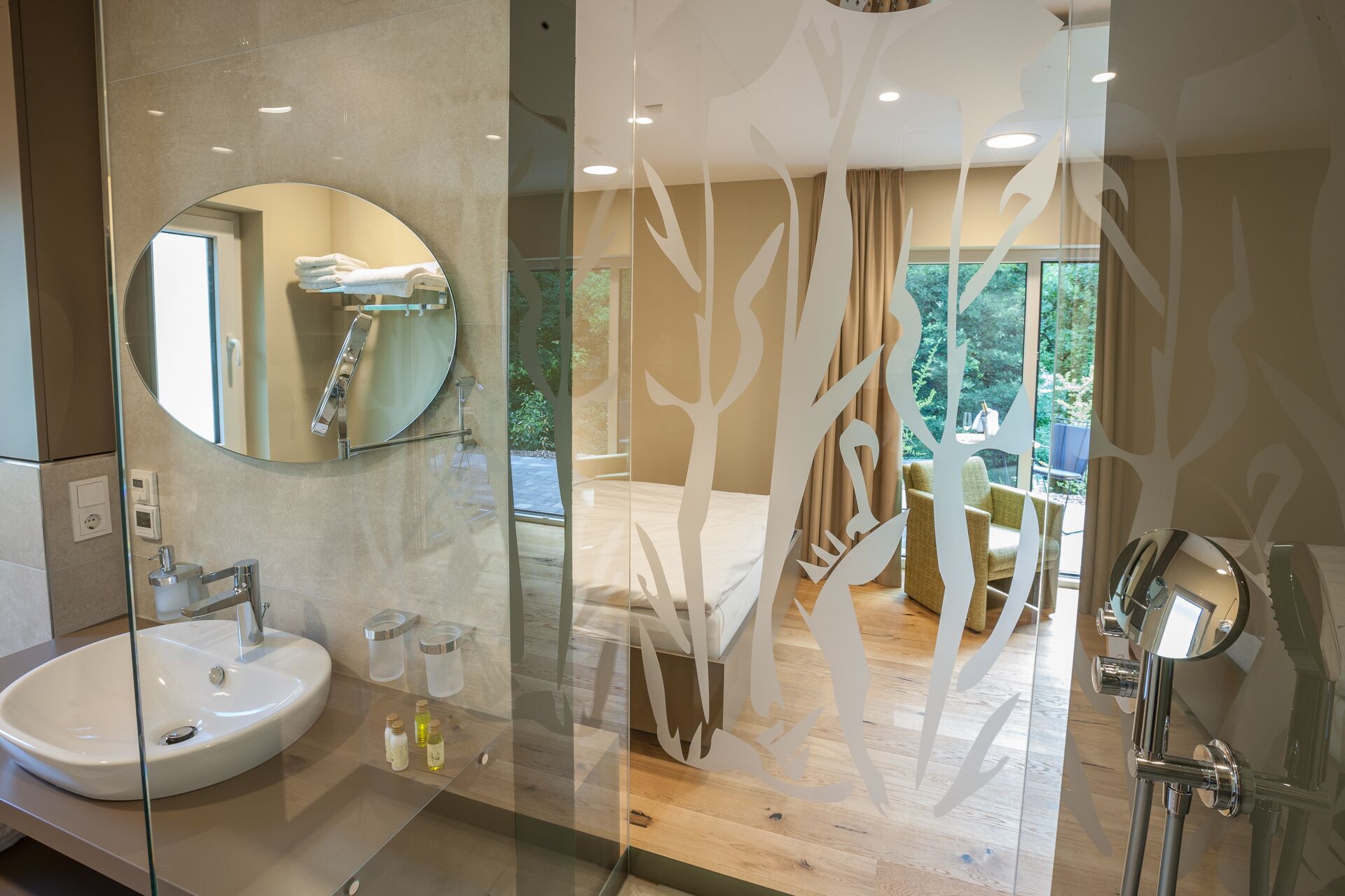 A modern bathroom with a round mirror, a white sink, and a glass partition.