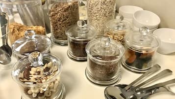 A variety of glass containers with lids, likely for storing food items, arranged on a table with several spoons and bowls.