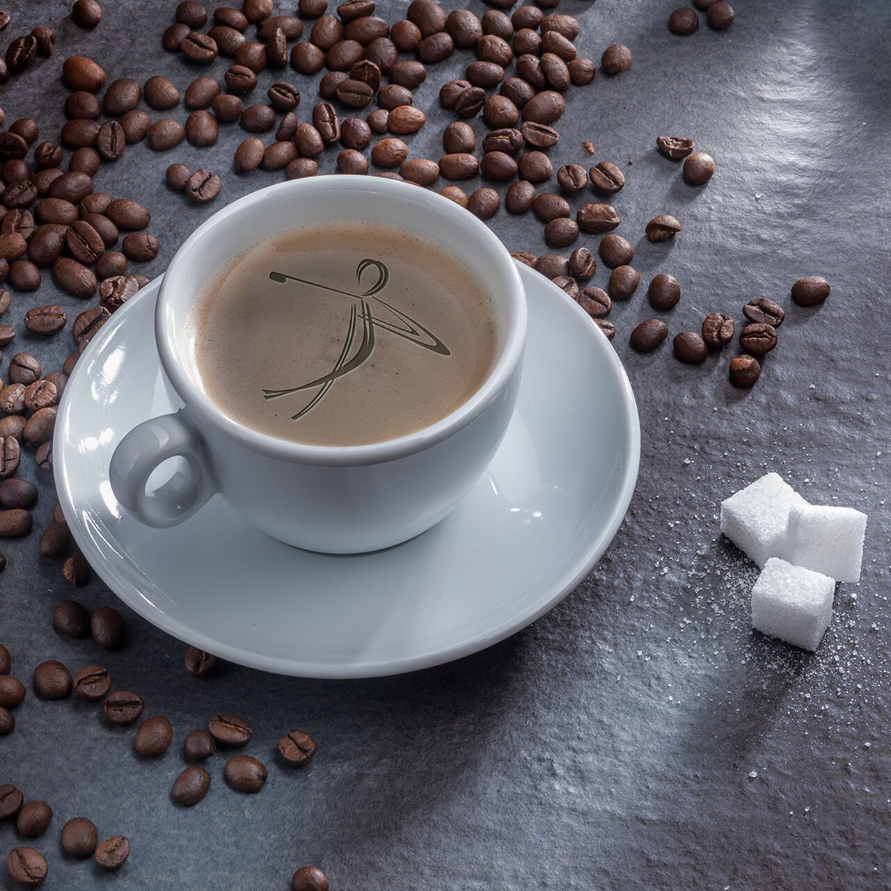 Eine Tasse Kaffee mit Latte-Art-Design, umgeben von Kaffeebohnen und Zuckerwürfeln auf einer strukturierten Oberfläche.