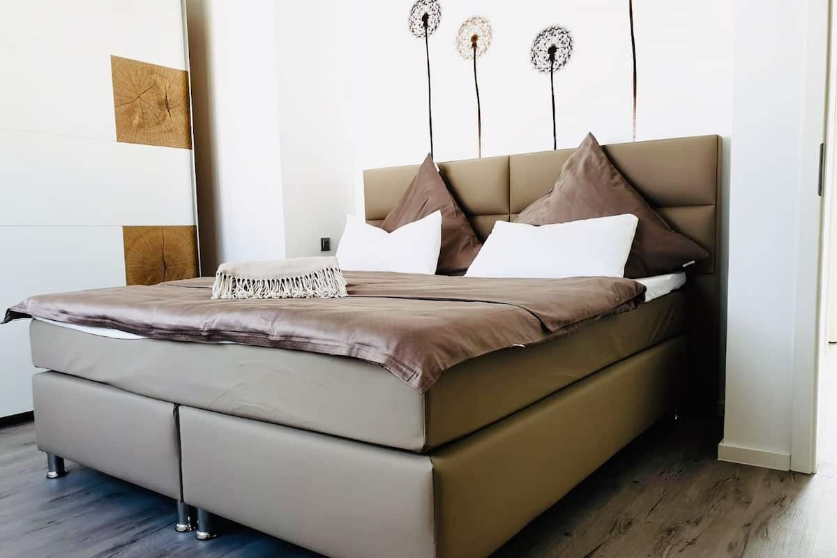 Een moderne slaapkamer met een groot bed, een houten hoofdbord en een decoratief wandobject.