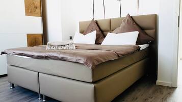 A modern bedroom with a large bed, a wooden headboard, and a decorative wall piece.