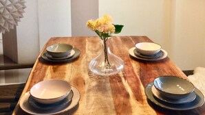 A dining table with a vase of flowers, plates, and a modern pendant light.