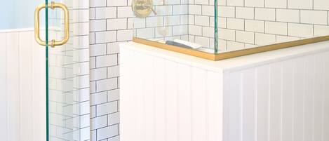 A modern bathroom with a glass-enclosed shower, white subway tiles, and a white vanity.