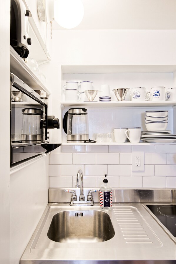 Una cocina moderna con electrodomésticos de acero inoxidable, salpicadero de azulejos blancos y horno empotrado.